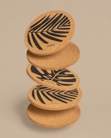 Stack of hand-carved wooden coasters made from black walnut, each with unique grain and finish.