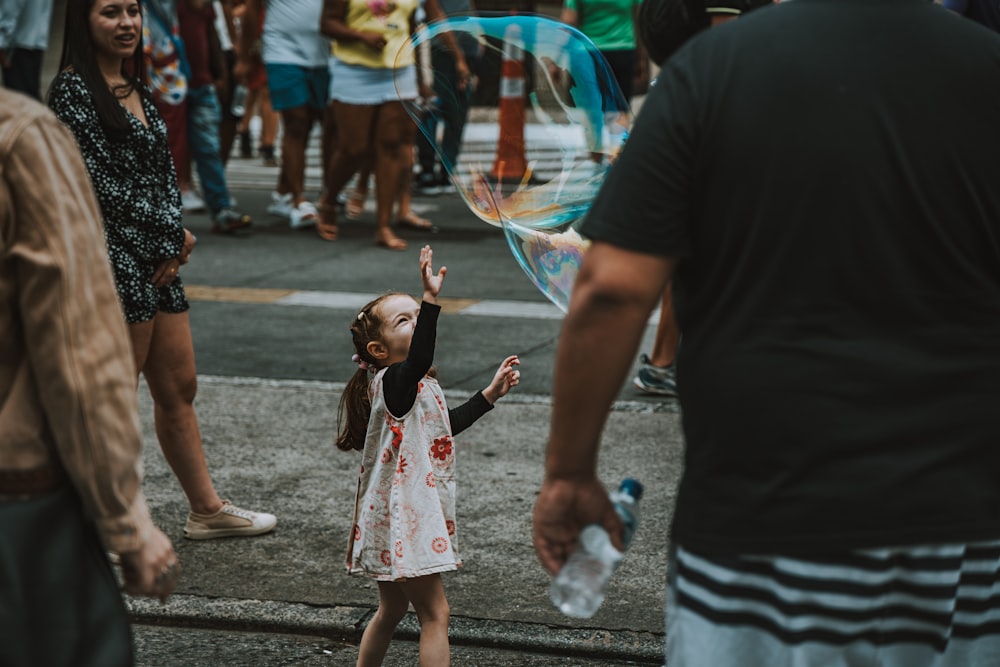 una bambina in un vestito bianco che gioca con un aquilone