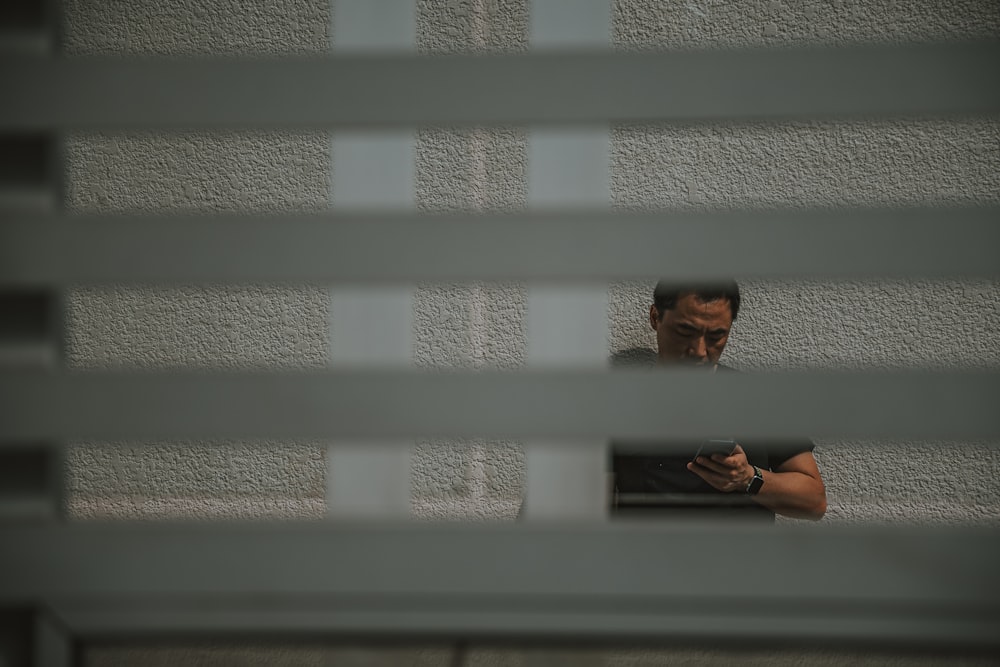a man looking at his cell phone through a window