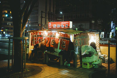A cozy street food stall with colorful lights at dusk.