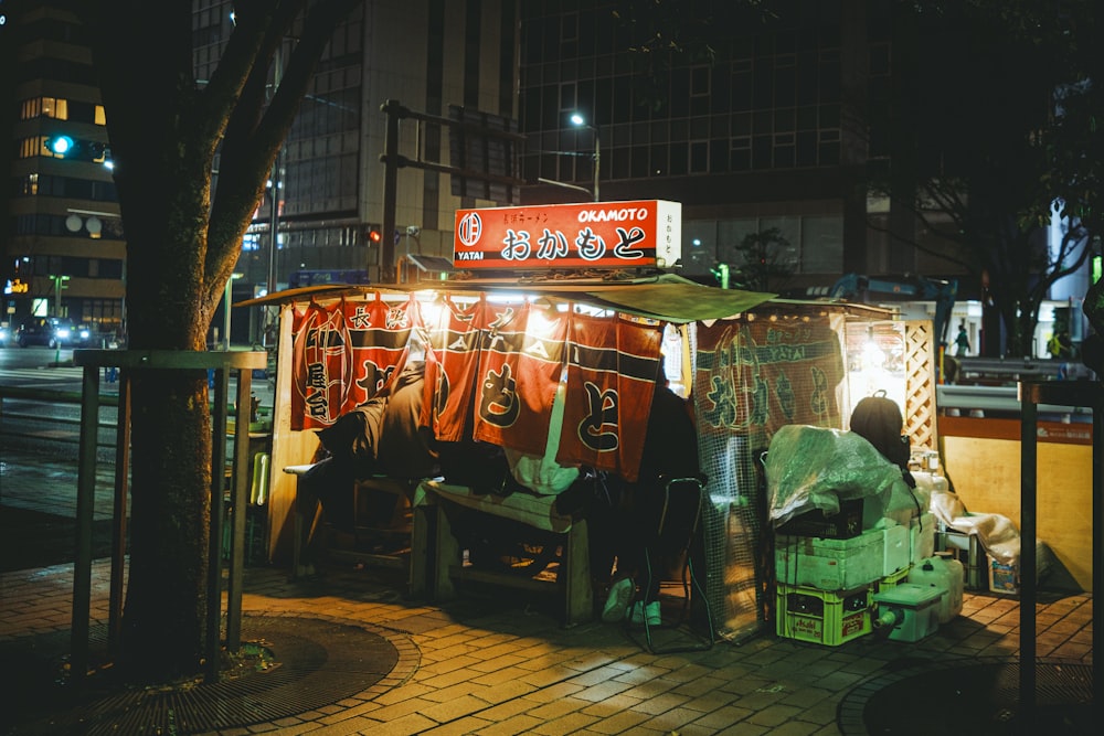 a man sitting on a bench in front of a food stand