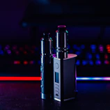 A midnight blue niteluxe vape vending machine illuminated by purple and pink neon lights inside a stylish club lounge.