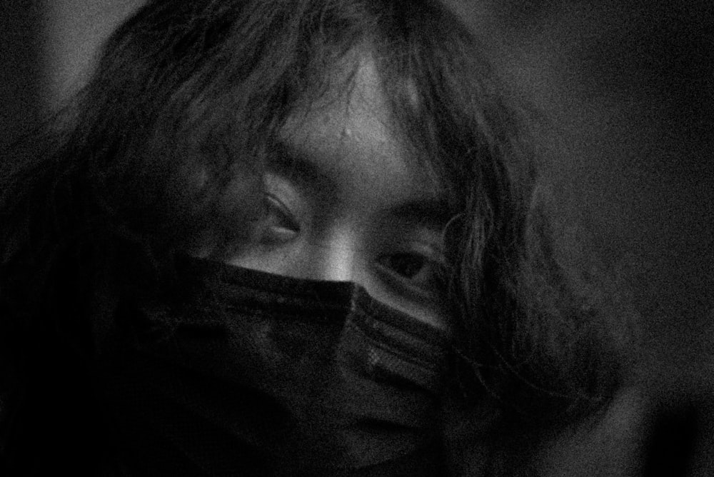 a black and white photo of a woman covering her face