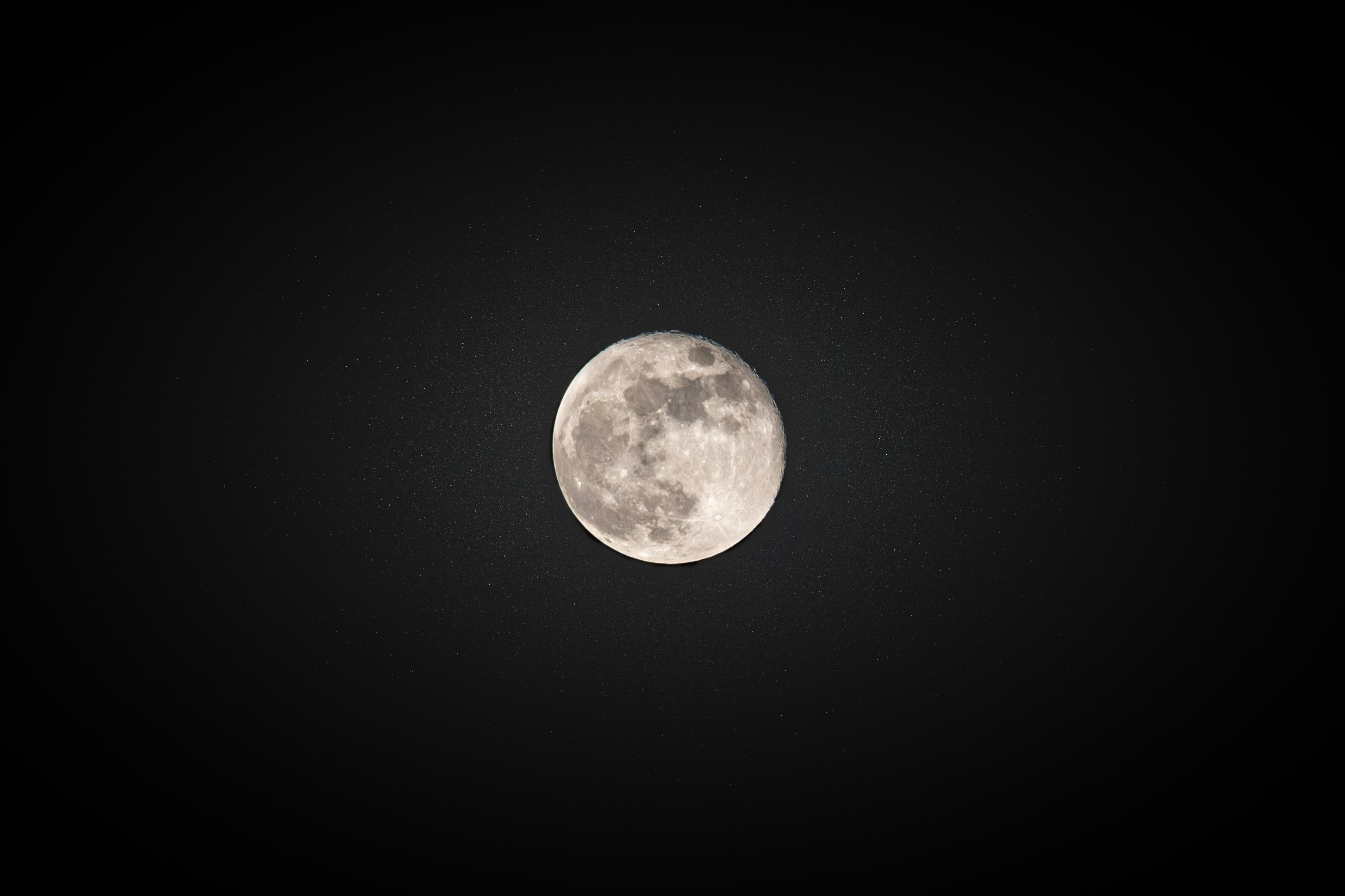 a full moon is seen in the dark sky