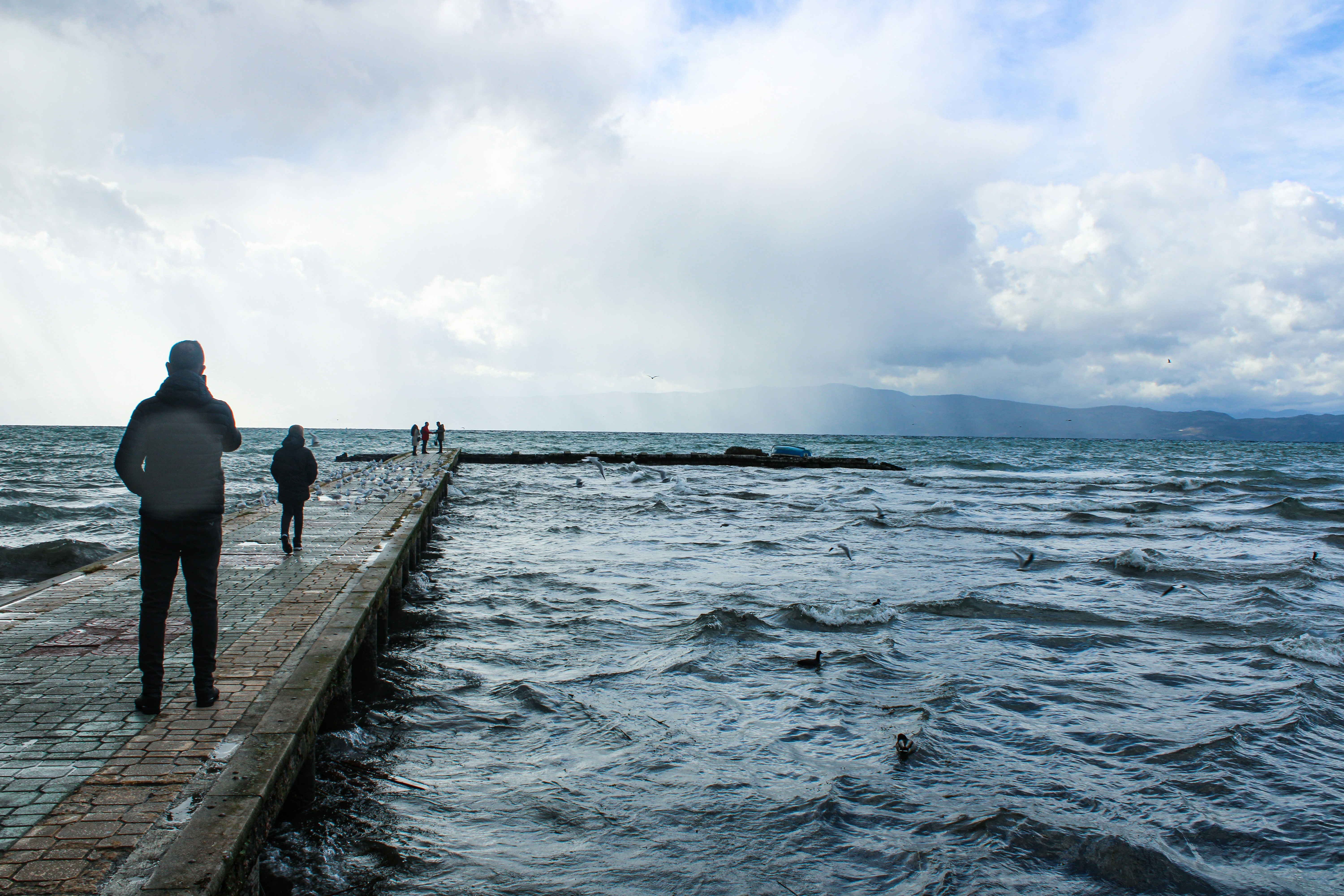 Une personne debout sur une jetée contemplant l eau calme, symbolisant la détente et les rencontres