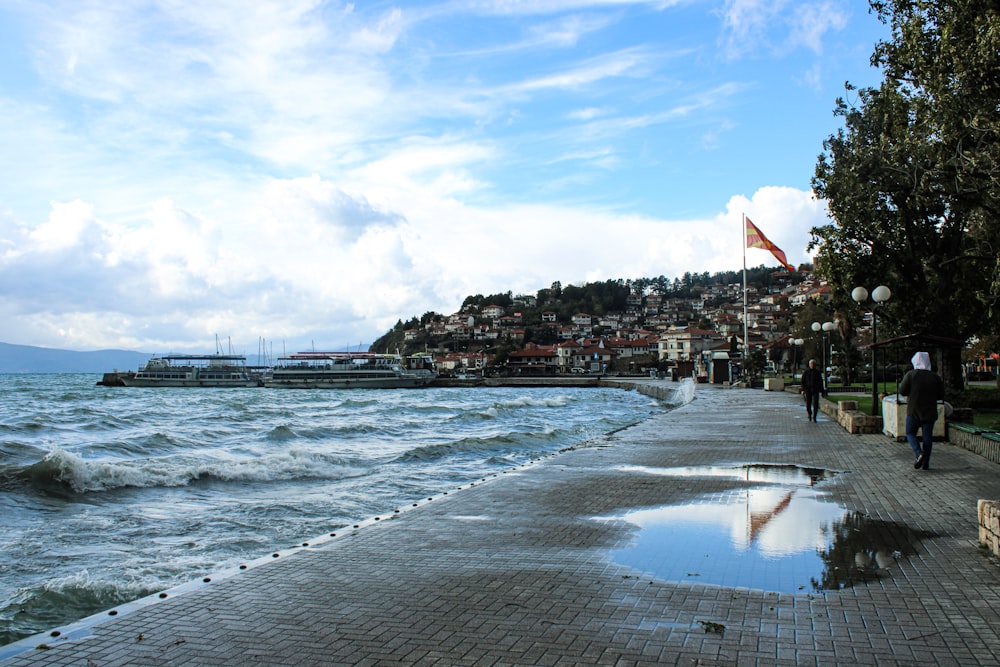 a man walking along a sidewalk next to the ocean