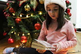 Children reading colorful Christmas books by a cozy fireplace