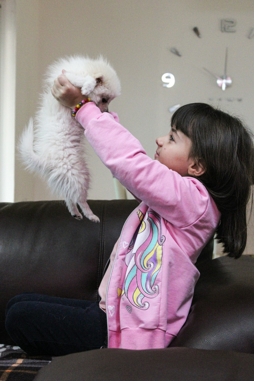 a little girl holding a white dog up to her face