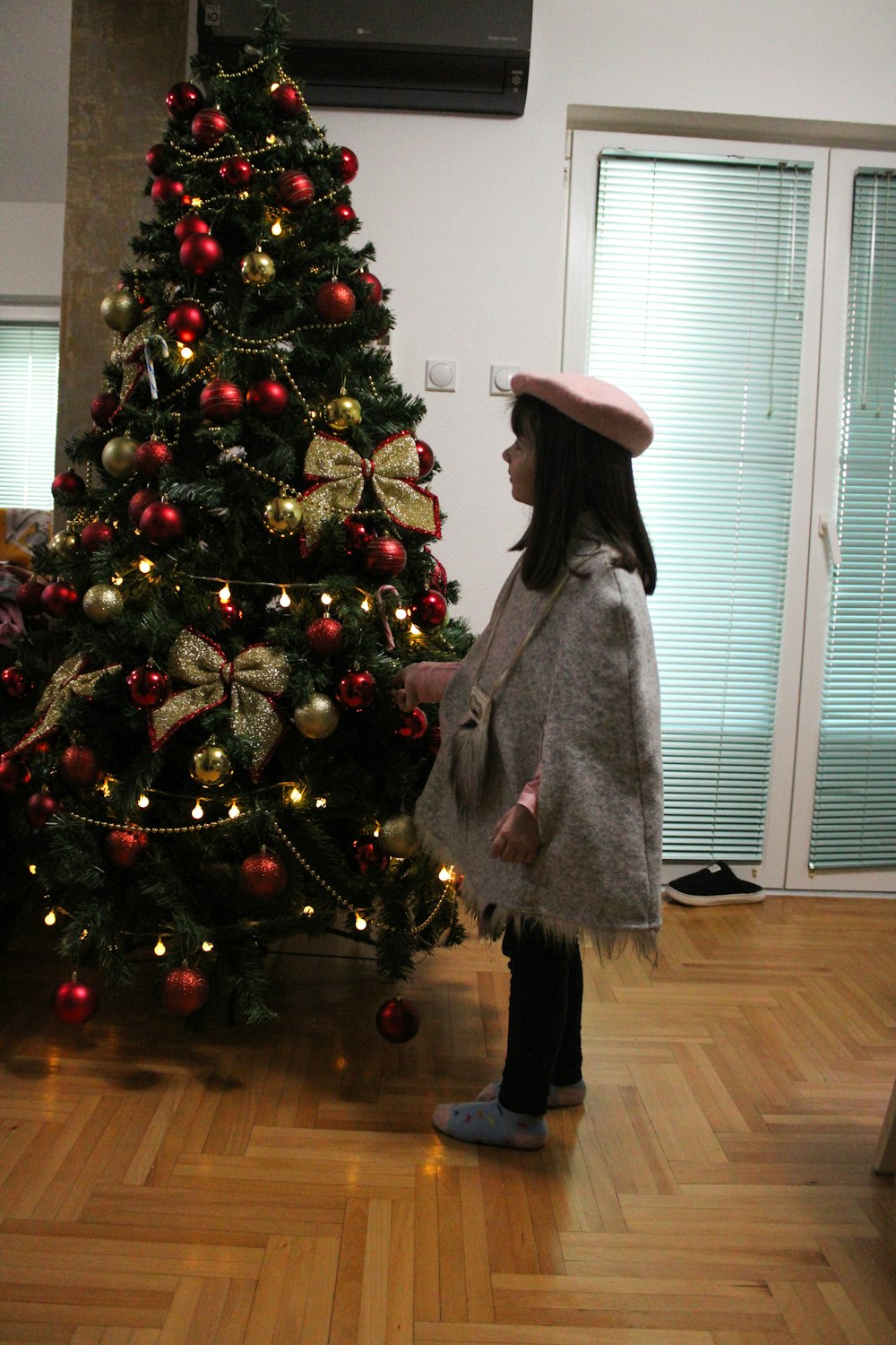 a little girl standing in front of a christmas tree