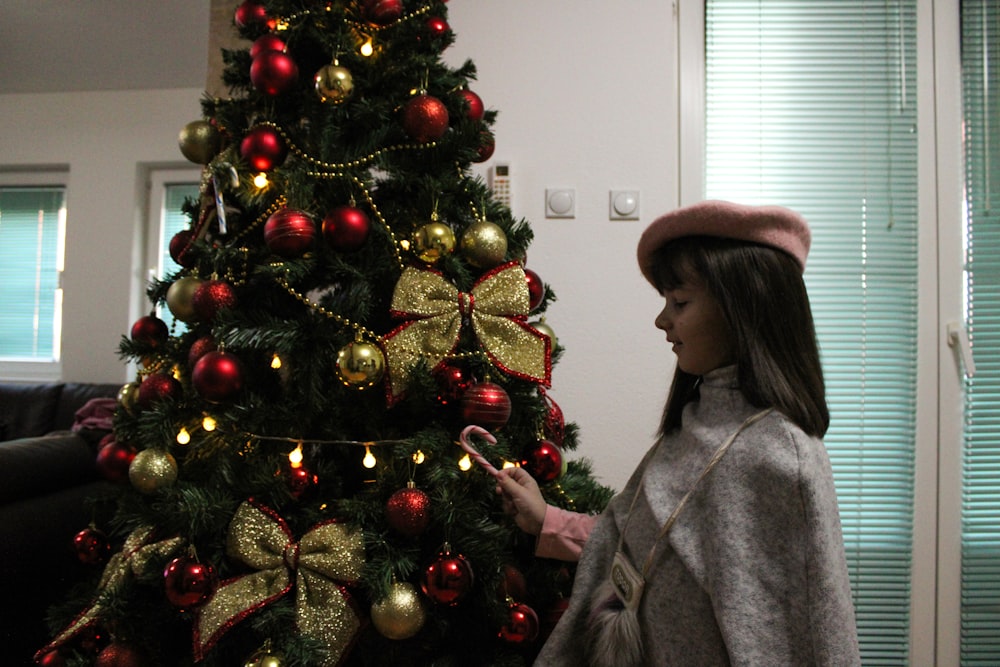 a woman standing in front of a christmas tree
