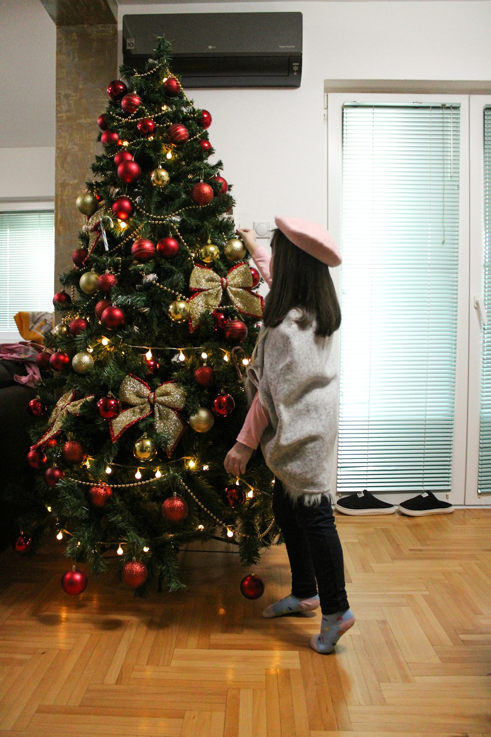 a little girl standing in front of a christmas tree
