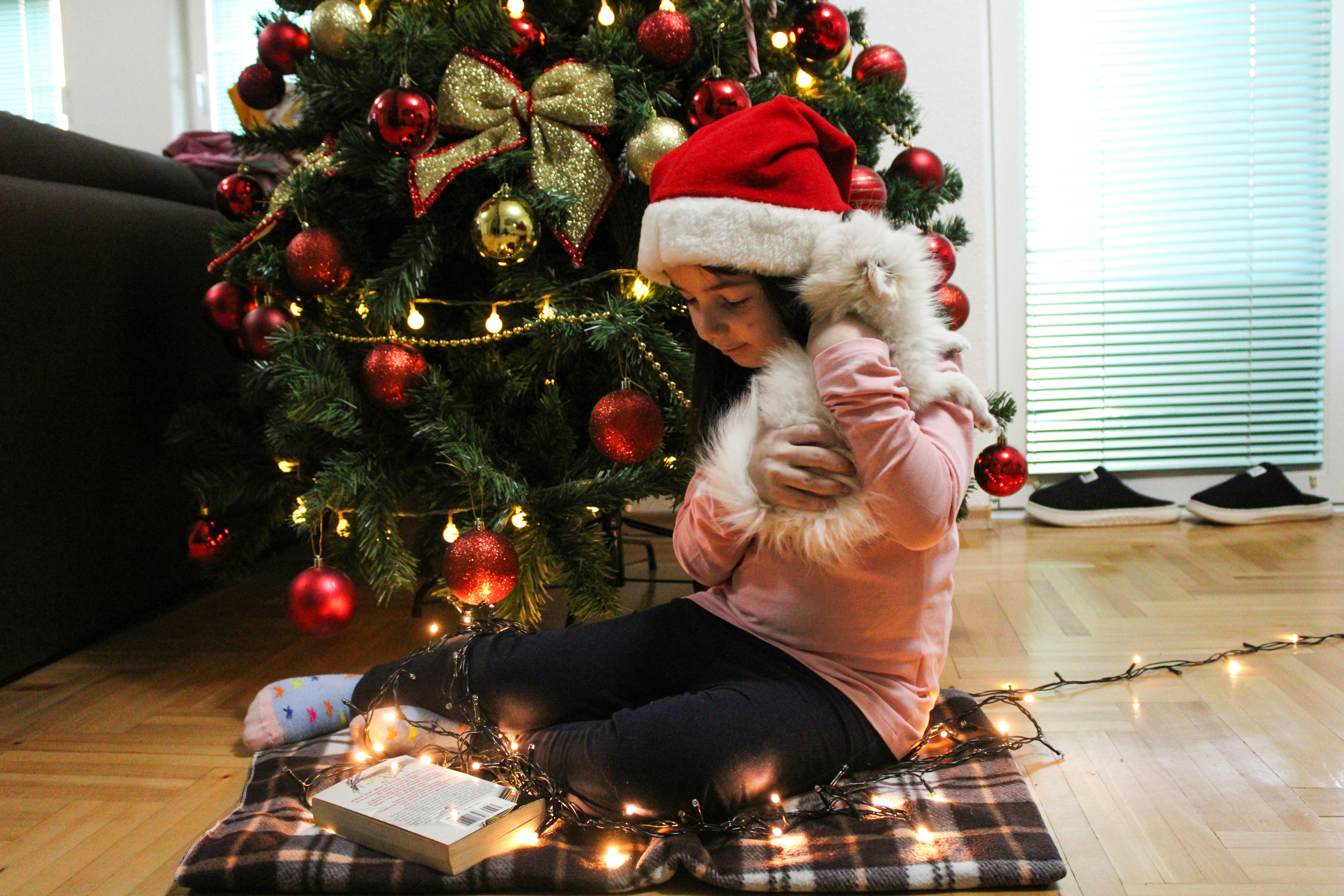 a little girl sitting on the floor next to a christmas tree