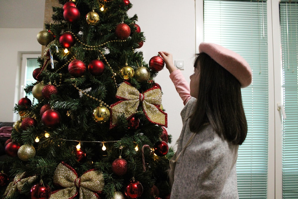 a little girl decorating a christmas tree