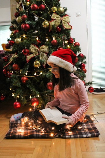 Children reading Christmas books together by a decorated fireplace.