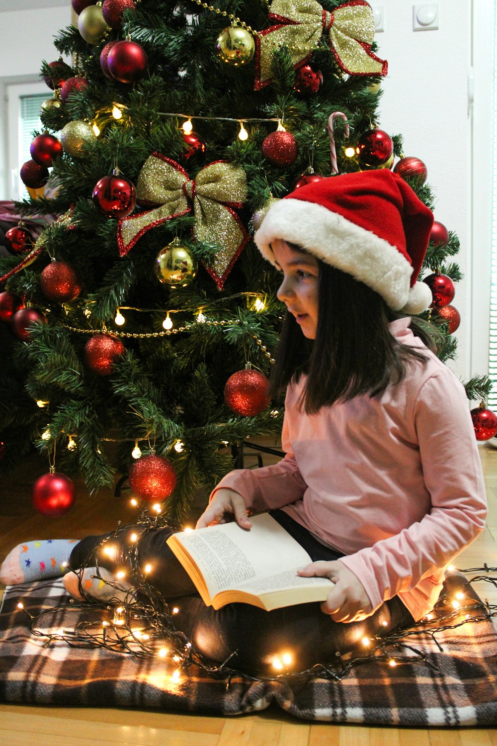 a little girl sitting on the floor reading a book