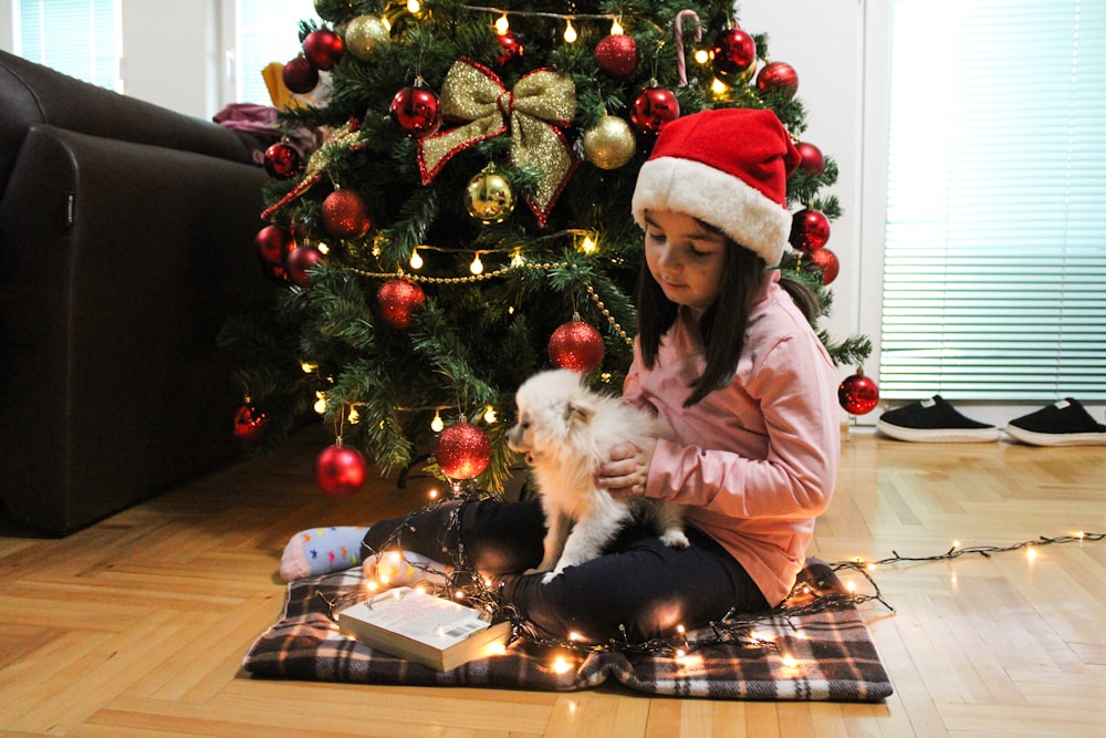 a little girl sitting on the floor with a dog