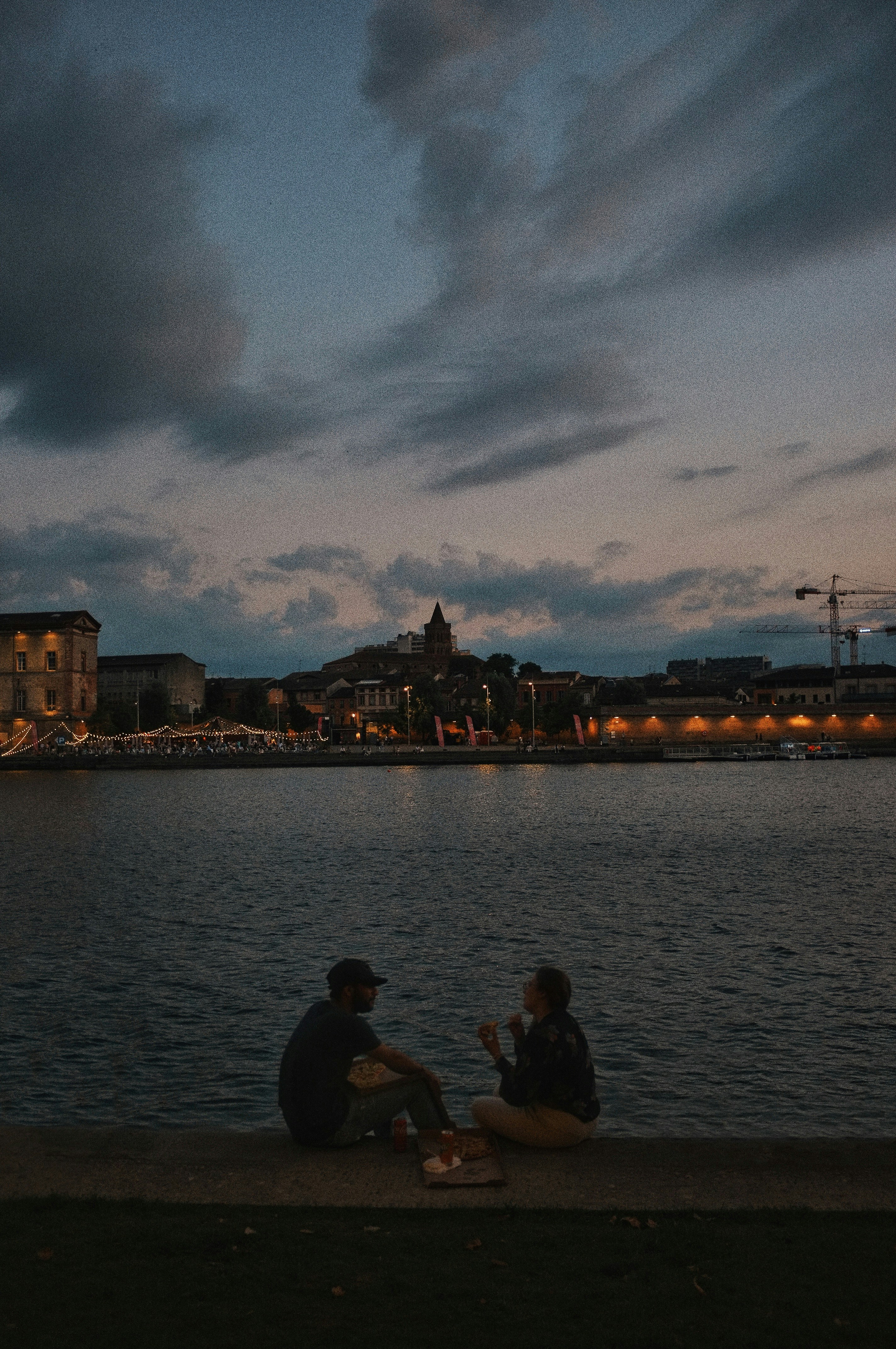Dos personas sentadas en el borde de un cuerpo de agua