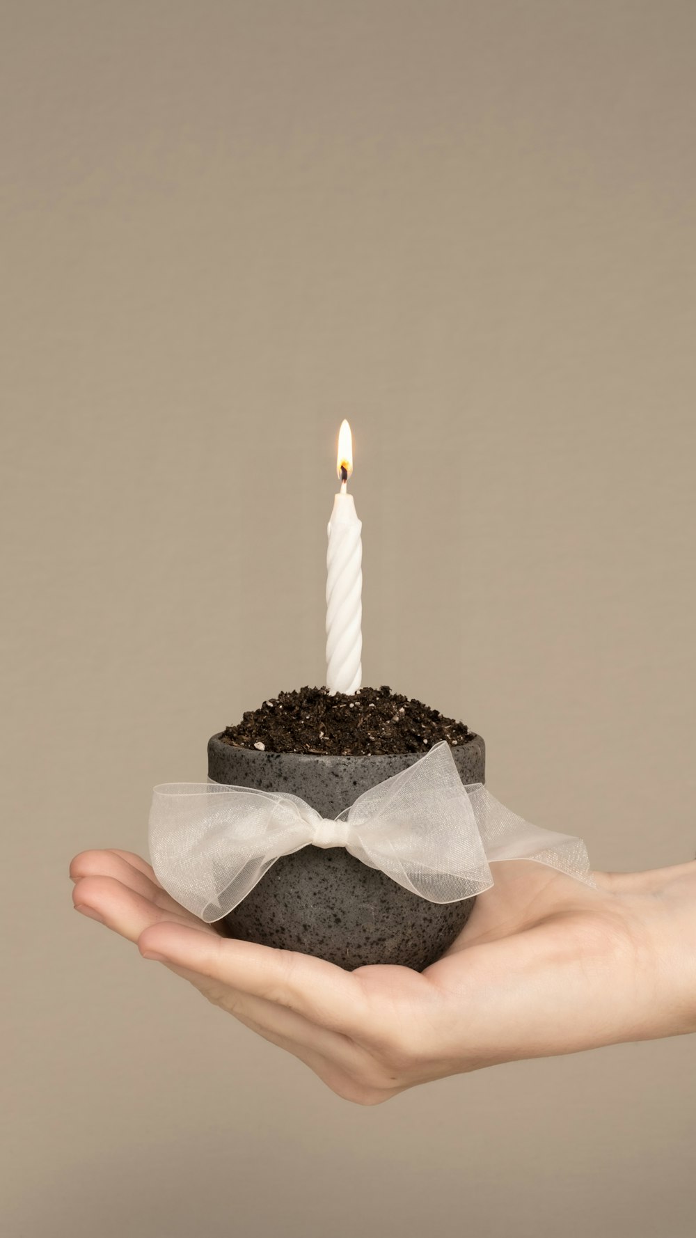 a person holding a cupcake with a candle in it