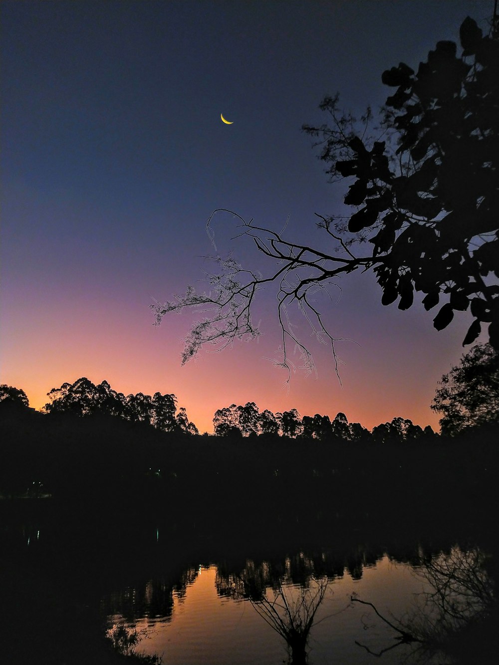 the moon is setting over a body of water