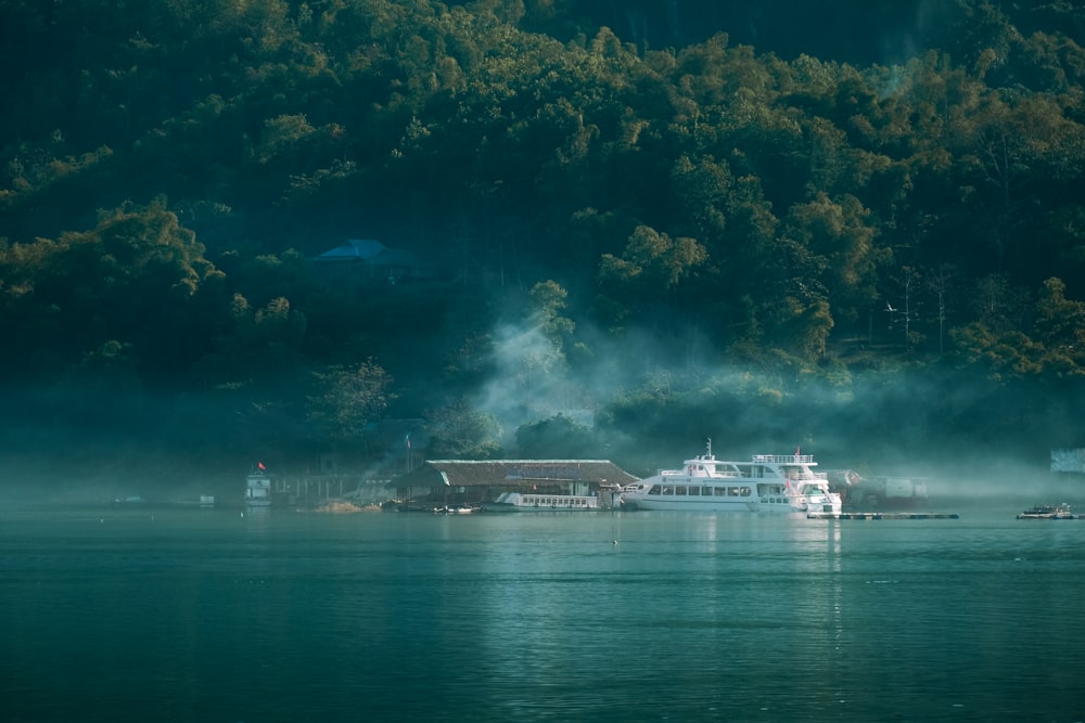 a large boat floating on top of a lake next to a forest