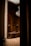 An ornate interior featuring intricate woodwork and a grand chandelier hanging from the ceiling. The space is elegantly lit, highlighting the detailed craftsmanship of the wooden staircase and decorative moldings.