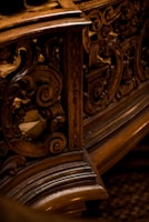 Intricate wooden carvings with swirling patterns, likely part of an ornate piece of furniture or architecture. The design showcases detailed craftsmanship with a focus on elegant curves and textures.