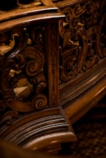 Intricate wooden carvings with swirling patterns, likely part of an ornate piece of furniture or architecture. The design showcases detailed craftsmanship with a focus on elegant curves and textures.