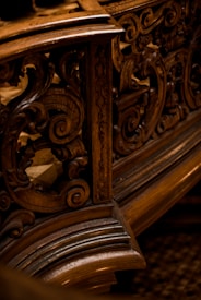 Intricate wooden carvings with swirling patterns, likely part of an ornate piece of furniture or architecture. The design showcases detailed craftsmanship with a focus on elegant curves and textures.