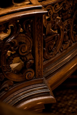 Intricate wooden carvings with swirling patterns, likely part of an ornate piece of furniture or architecture. The design showcases detailed craftsmanship with a focus on elegant curves and textures.