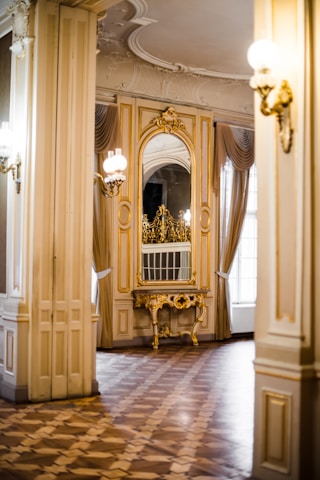A bright, airy room featuring various decorative mirrors on the walls, reflecting natural light and enhancing the space's elegance.
