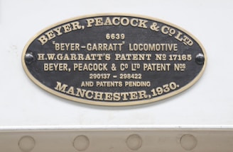An oval metallic plaque displaying text, including the name Beyer, Peacock & Co. Ltd and details about a Beyer-Garratt locomotive. It mentions patents associated with H.W. Garratt and has patent numbers 17165, 290137, and 298422. The plaque is dated Manchester, 1930.