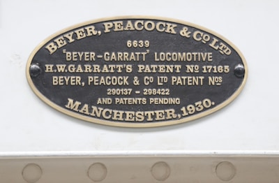 An oval metallic plaque displaying text, including the name Beyer, Peacock & Co. Ltd and details about a Beyer-Garratt locomotive. It mentions patents associated with H.W. Garratt and has patent numbers 17165, 290137, and 298422. The plaque is dated Manchester, 1930.