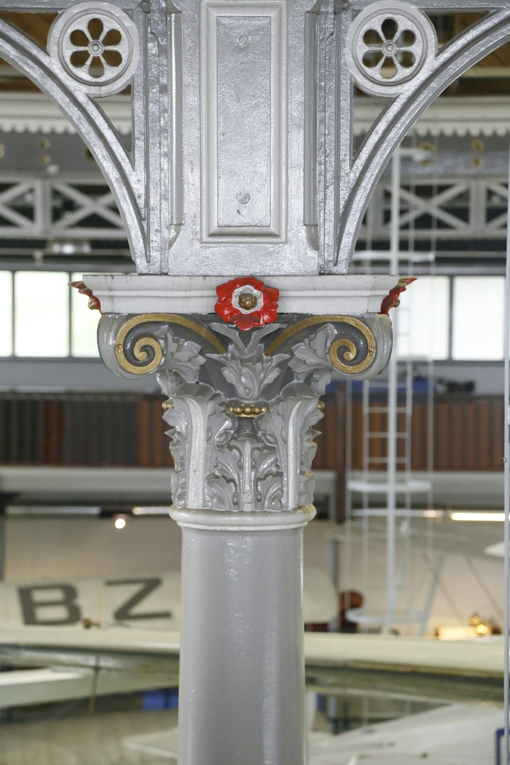 a white pillar with a red flower on top of it