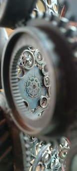 Intricate gears and cogs are interconnected and layered, creating a complex mechanical structure. The view is focused and detailed, showing various sizes of interlocking circular metal pieces.