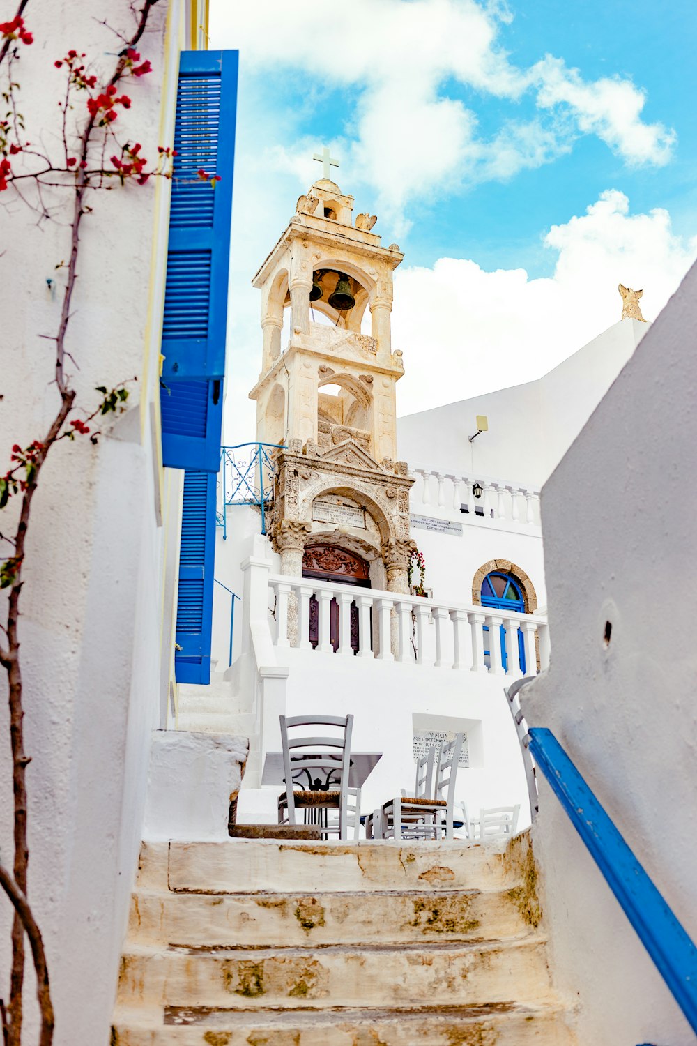 un edificio blanco con persianas azules y una torre del reloj