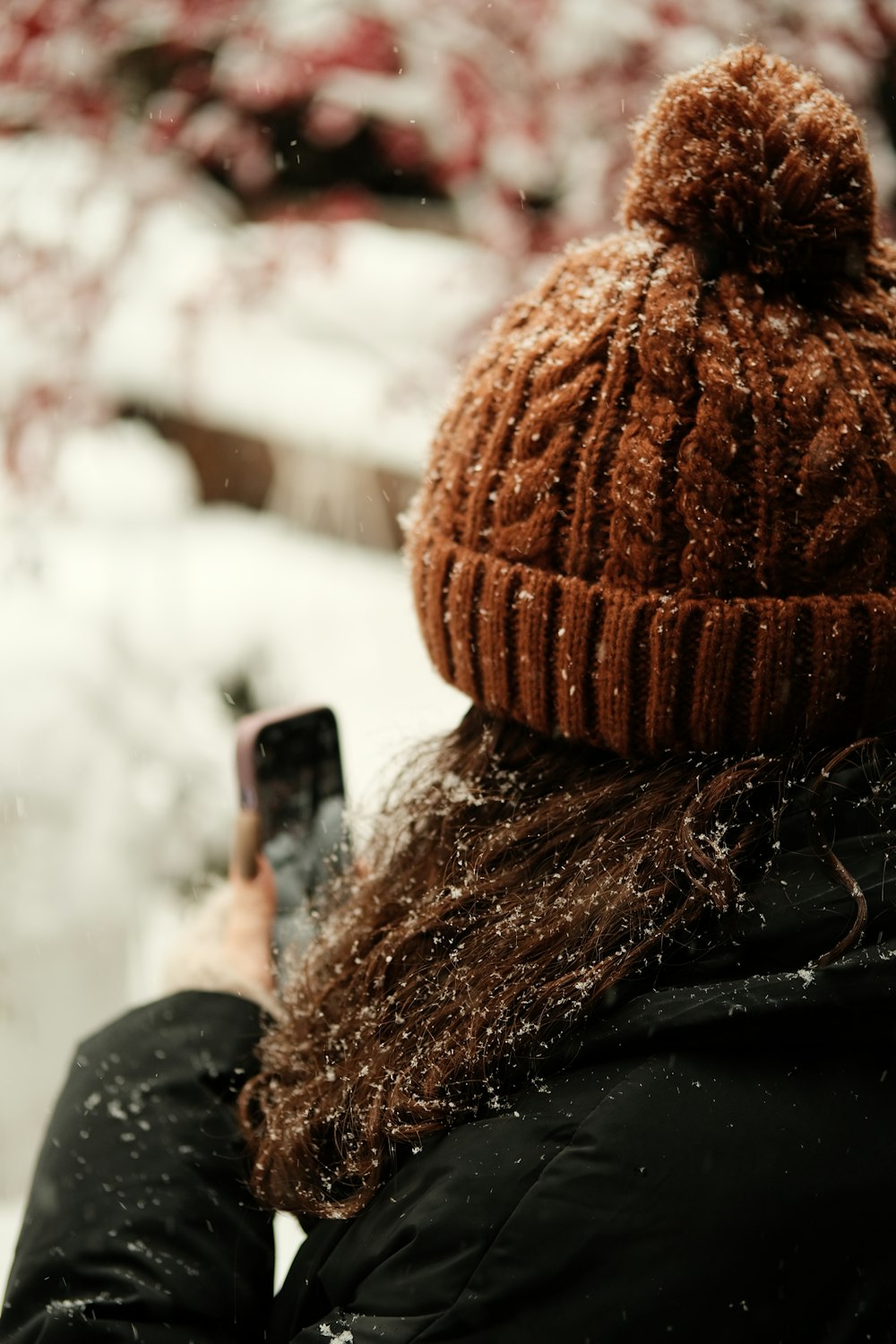 a woman wearing a brown hat and holding a cell phone