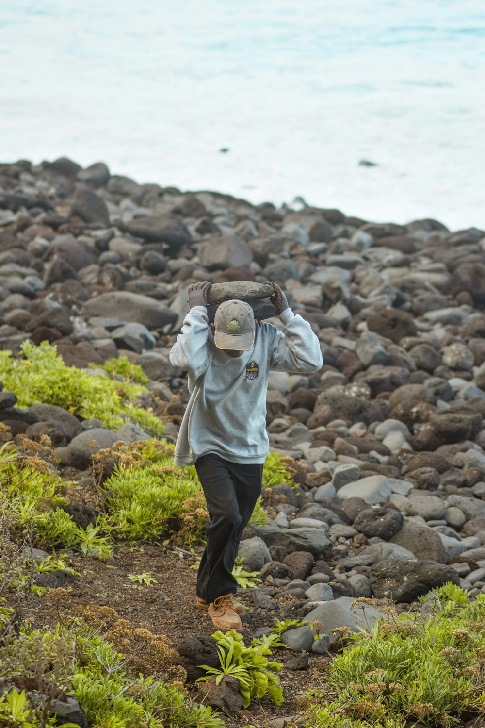 a person walking on a rocky beach with a hat on