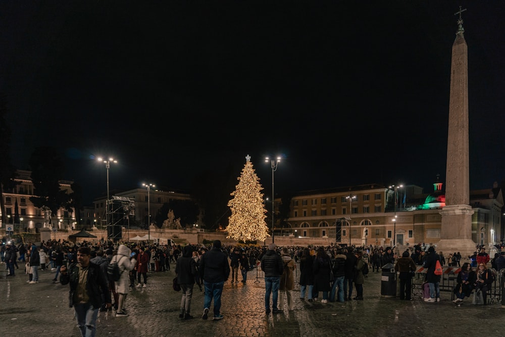 a large group of people standing around a christmas tree