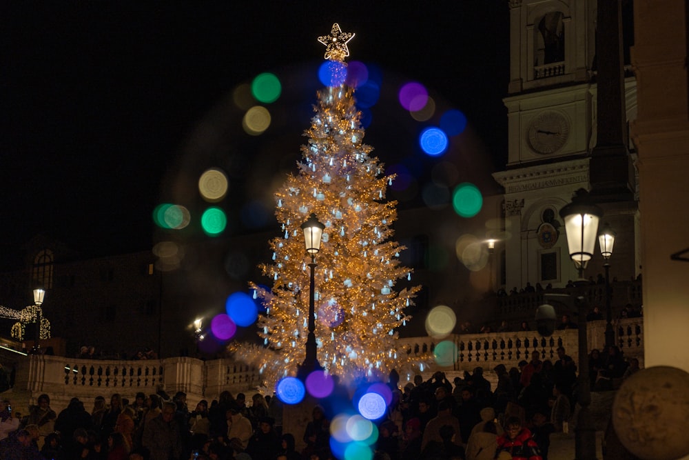 a lit christmas tree in front of a crowd of people