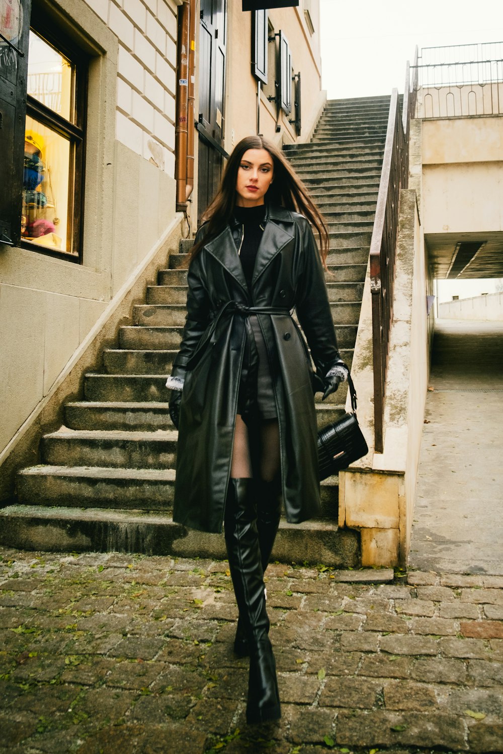 a woman in a trench coat is walking down the street