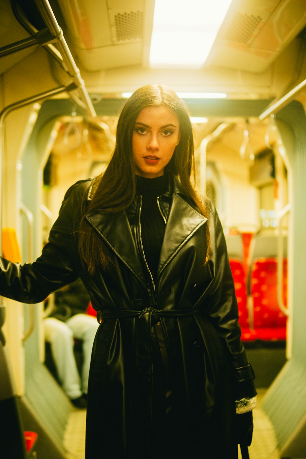 a woman in a black leather coat standing on a train