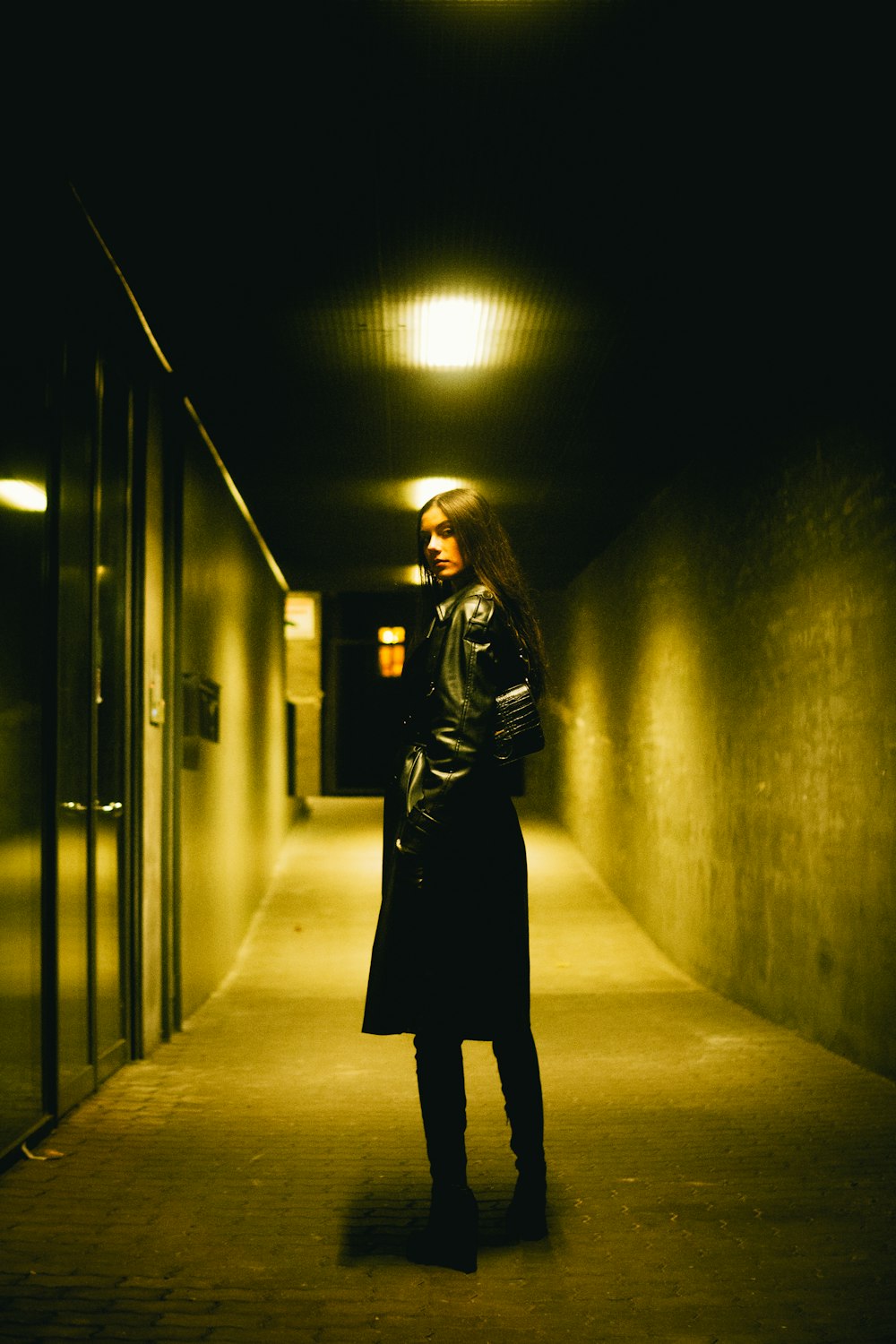 a woman in a long black coat standing in a hallway