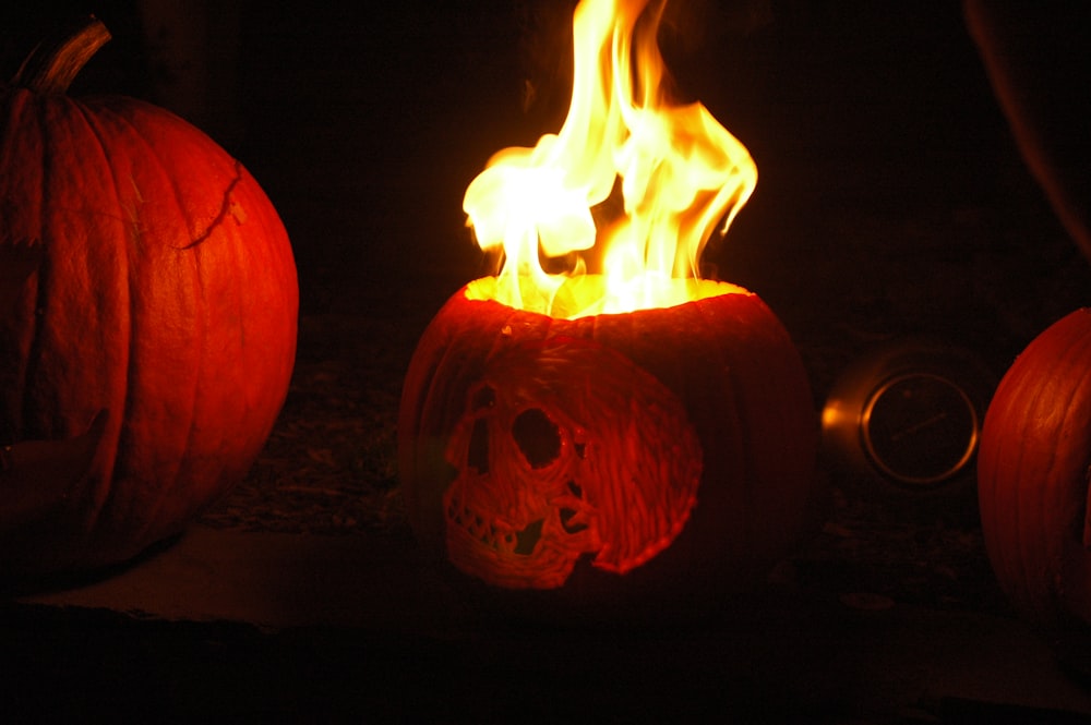two carved pumpkins with flames burning inside of them