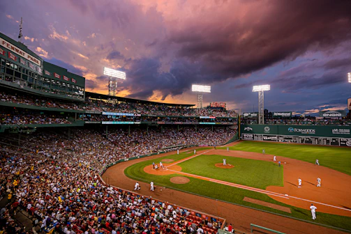 A baseball pitcher winding up for a fastball, framed by a dark, moody sky and glowing stadium lights.