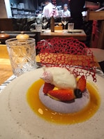 Chef carefully plating a delicate dessert with chocolate and fresh berries in a sophisticated kitchen.