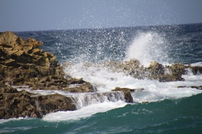 a wave crashes against the rocks in the ocean