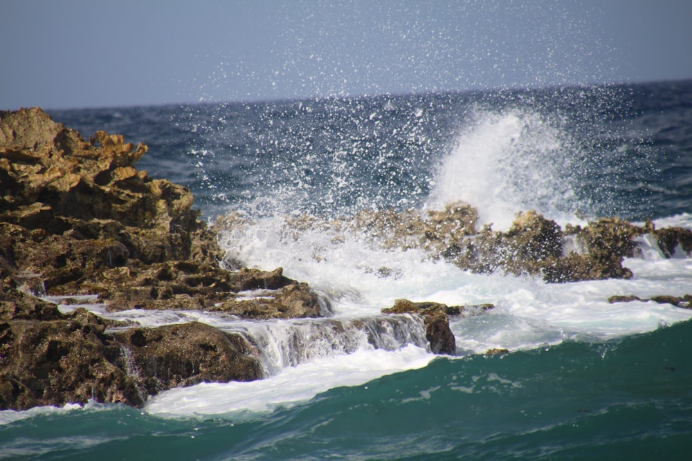 Uma onda bate contra as rochas do oceano