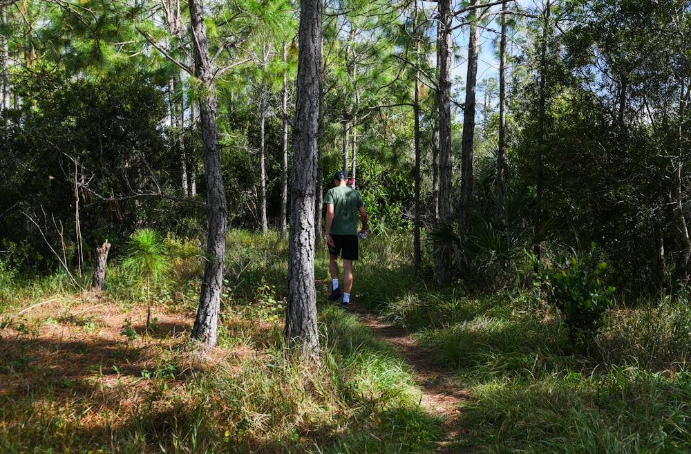 a man walking through the woods on a trail