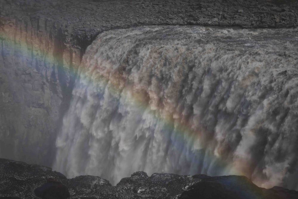 a rainbow in the sky over a waterfall