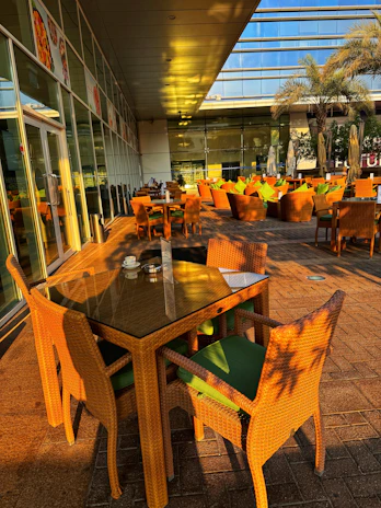 Outdoor seating area of Brisacafé with green plants and sunlight.
